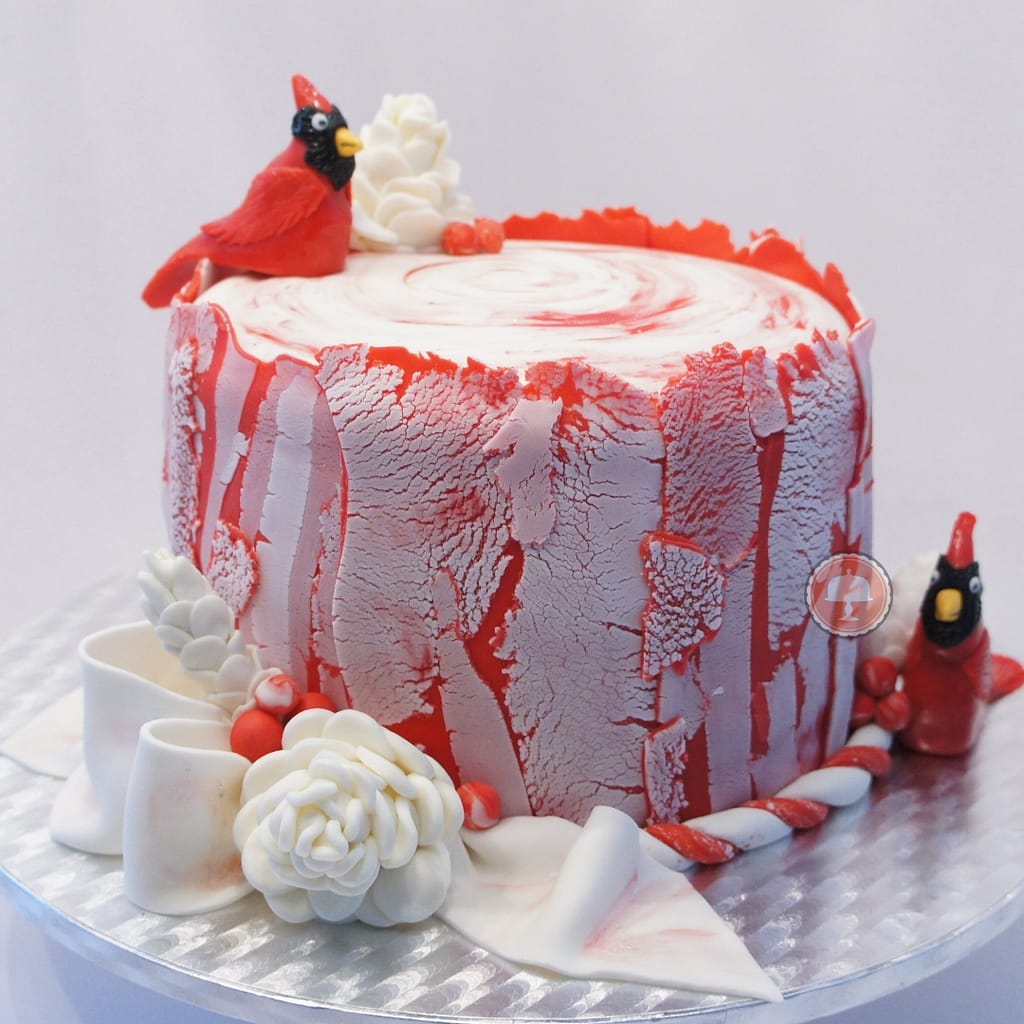 cardinal cake with fondant red cardinals white pinecones red berries white bow on a tree stump