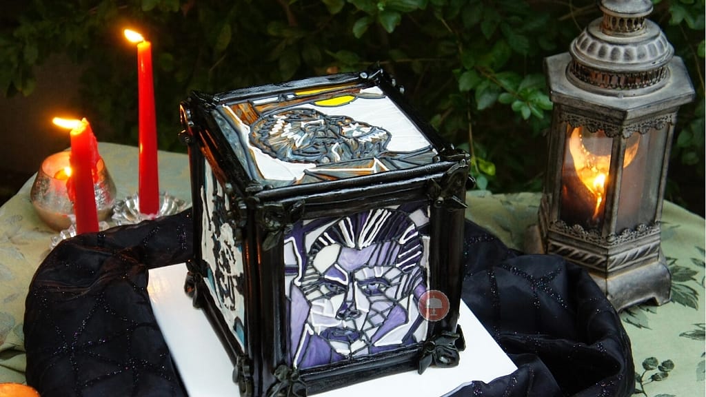 Halloween cake sitting on a party table showing the universal monsters.  Cake is made using a stained glass piping technique.  